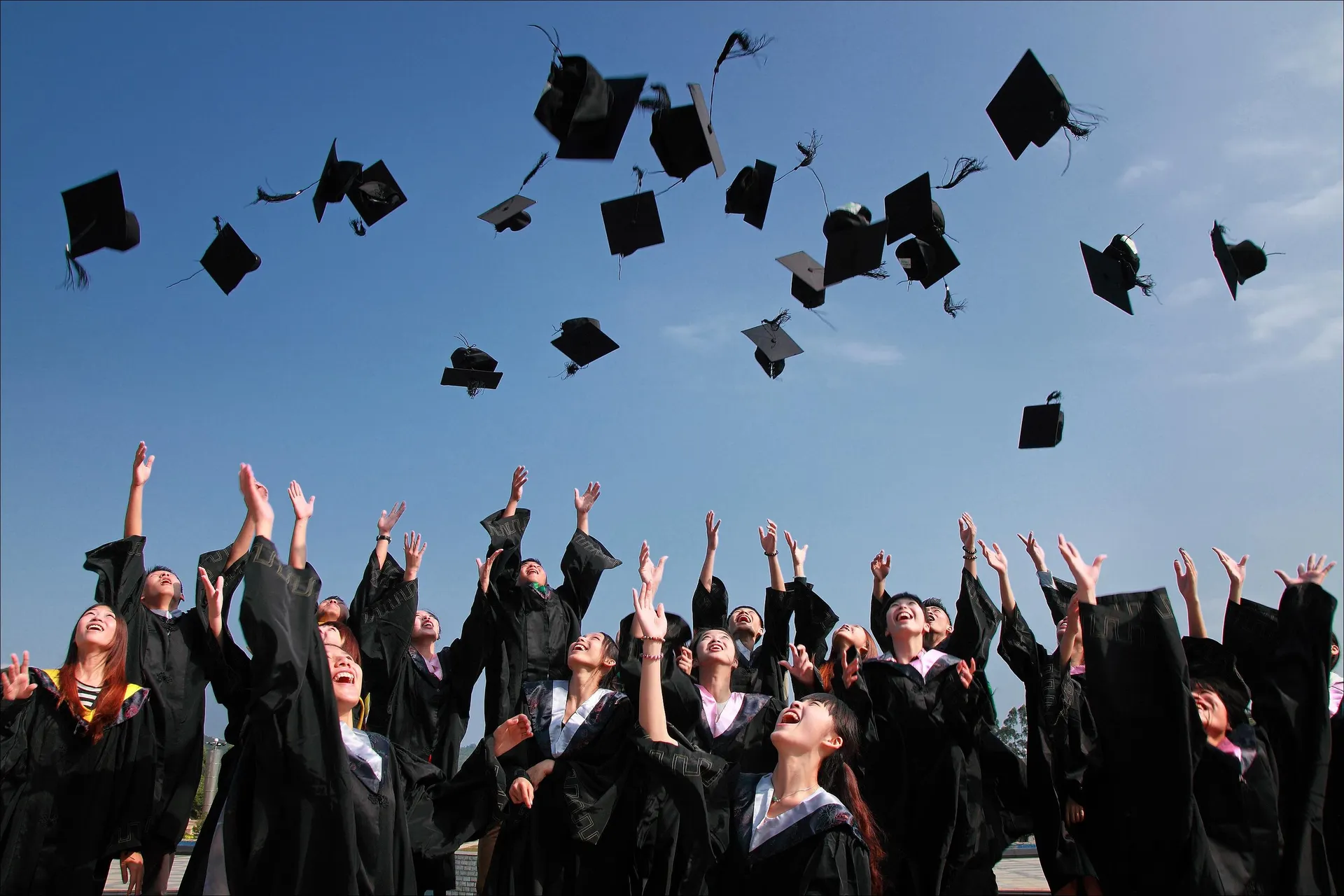 Graduating students celebrating together and throwing their caps into the sky